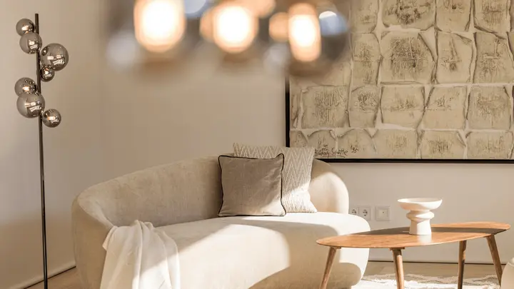 Wohnbereich mit geschwungenem Sofa und großem Wandbild nach dem Home Staging