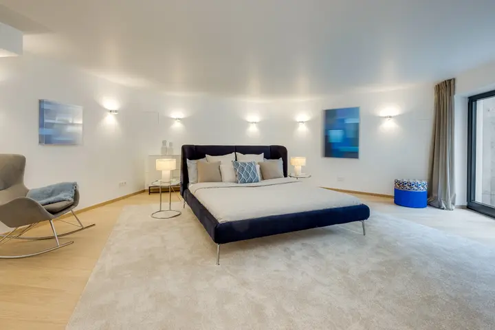 Schlafzimmer mit Polsterbett, Teppich und Wandleuchten nach dem Home Staging