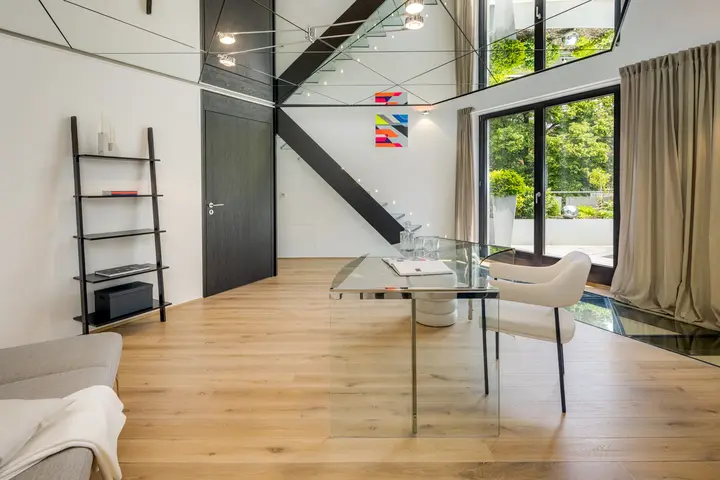 Arbeitsplatz mit Glastisch unter einer Galerie mit Treppe