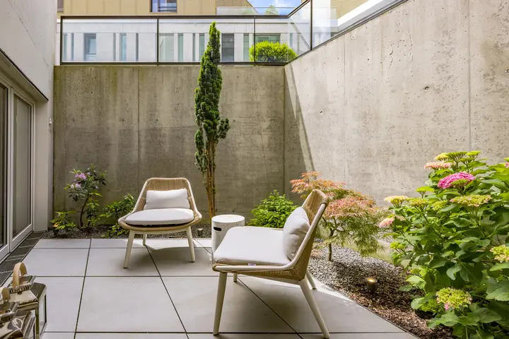 Innenhof aus Sichtbeton mit zwei Sesseln und Pflanzen
