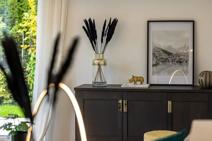 Dunkles Sideboard mit Wandbild und Pampasgras