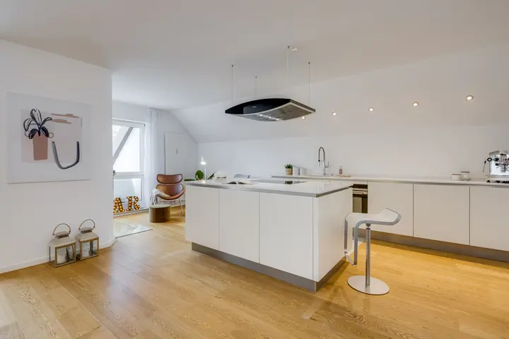 Küche mit Kochinsel und Barhocker in einer Dachgeschosswohnung