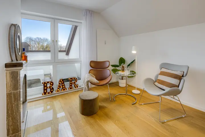 Wohnbereich mit Lounge-Sessel und Kamin im Dachgeschoss