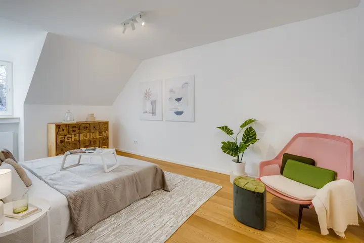 Schlafzimmer unter der Dachschräge mit Bett und Sessel