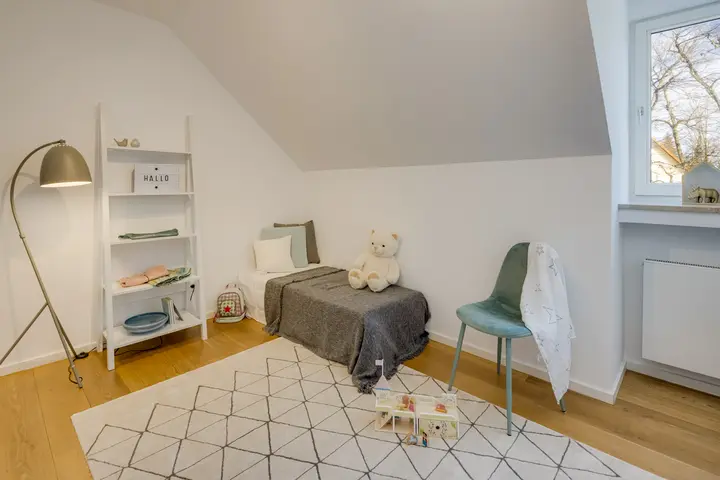Kinderzimmer unter der Dachschräge mit Bett und Teppich