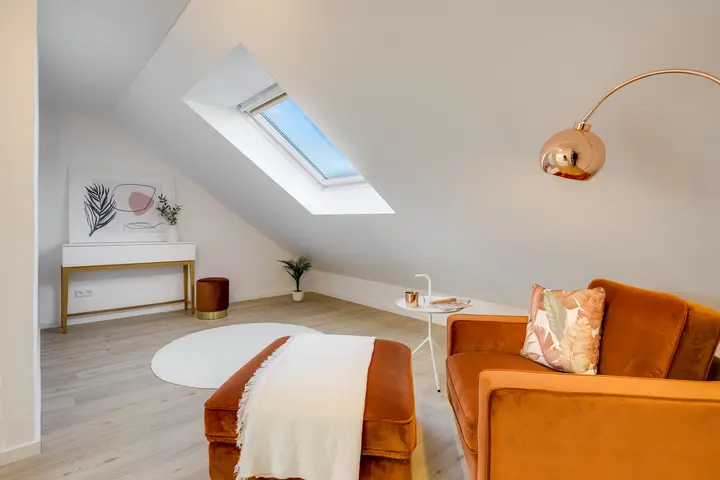 Zimmer unter dem Dachfenster mit Sessel und Bogenleuchte